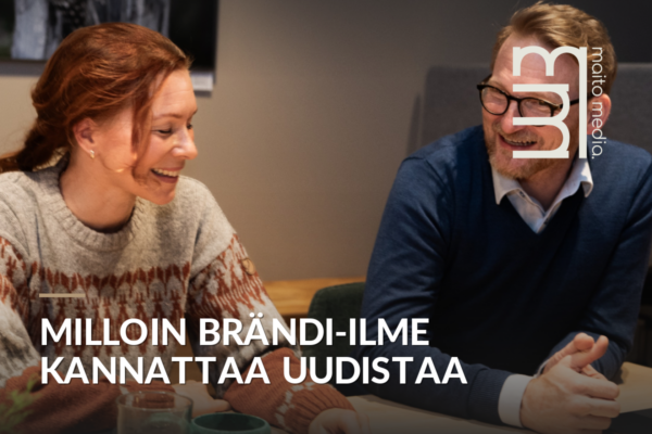 Kaksi henkilöä istuu pöydän ääressä ja keskustelee hymyillen