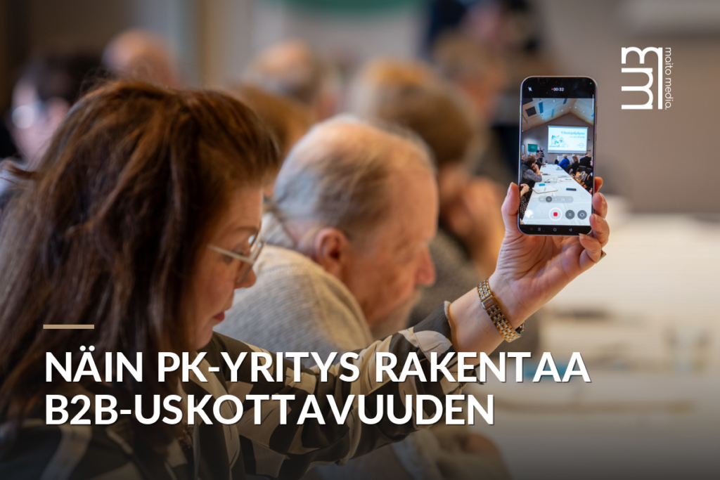Nainen ottaa videota puhelimella tapahtumassa, taustalla muita osallistujia